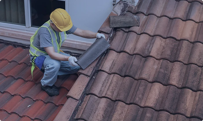 Couvreur réparant tuiles cassées